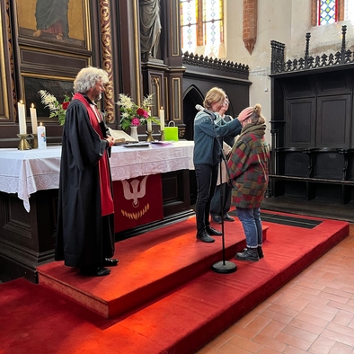 Person segnet eine neue Mitarbeiterin in einer Kirche vor dem Altar