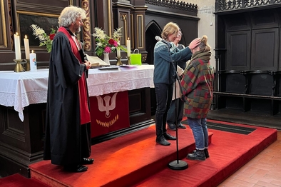 Person segnet eine neue Mitarbeiterin in einer Kirche vor dem Altar